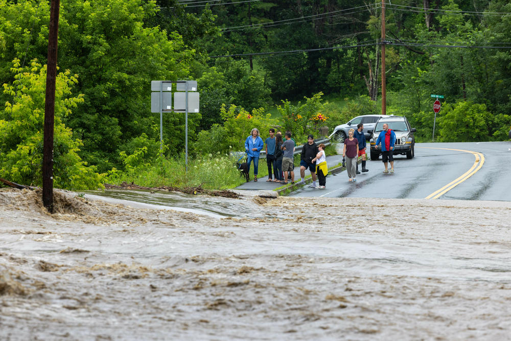 Onlookers check out a flooded road on Monday, July 10, in Chester, Vt.
