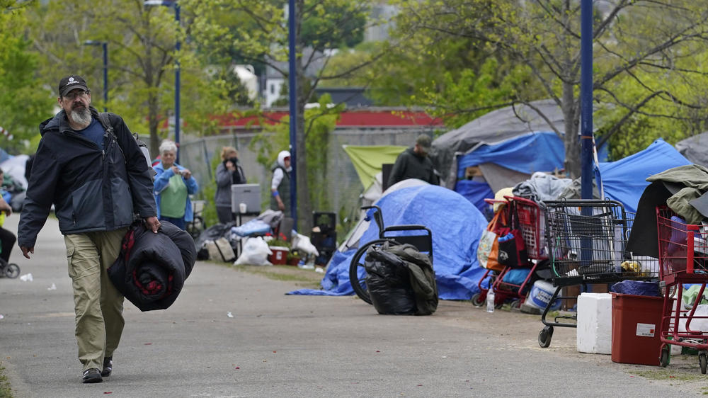 A man carries a sleeping bag at a homeless encampment in Portland, Maine, in May, before city workers arrived to clean the area. State officials say a lack of affordable housing is behind a sharp rise in chronic homelessness.