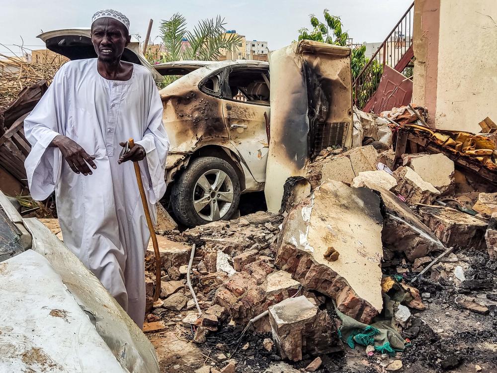 A man inspects damage as he walks through the rubble by a destroyed car outside a house that was hit by an artillery shell in the Azhari district in the south of Khartoum on June 6, 2023.