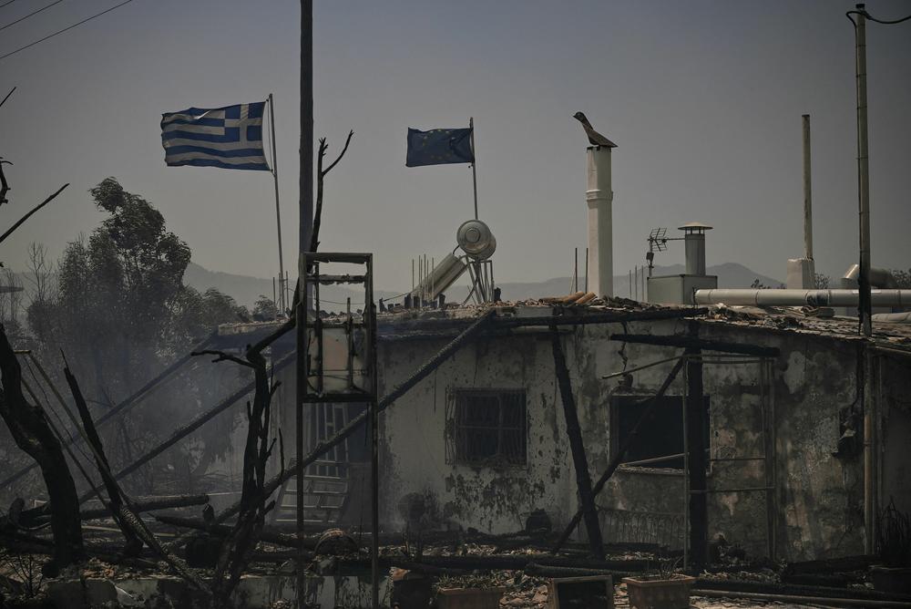 July 24, 2023: This photograph shows fluttering Greek and European flags on a burnt building amid a fire between the villages of Kiotari and Genadi, on the Greek island of Rhodes.