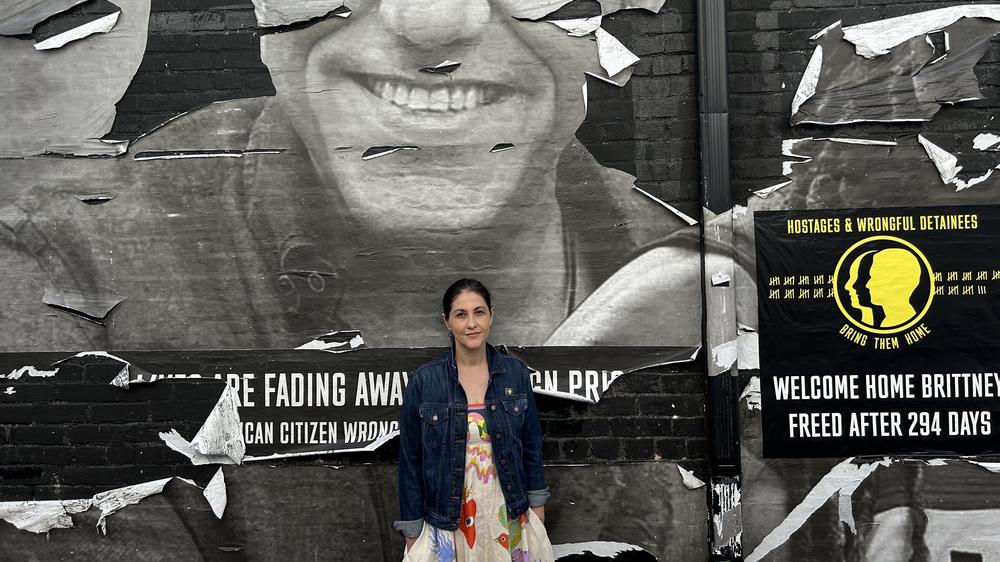 Neda Sharghi in front of a Washington, D.C. mural showing her brother Emad Sharghi, and other Americans imprisoned overseas.