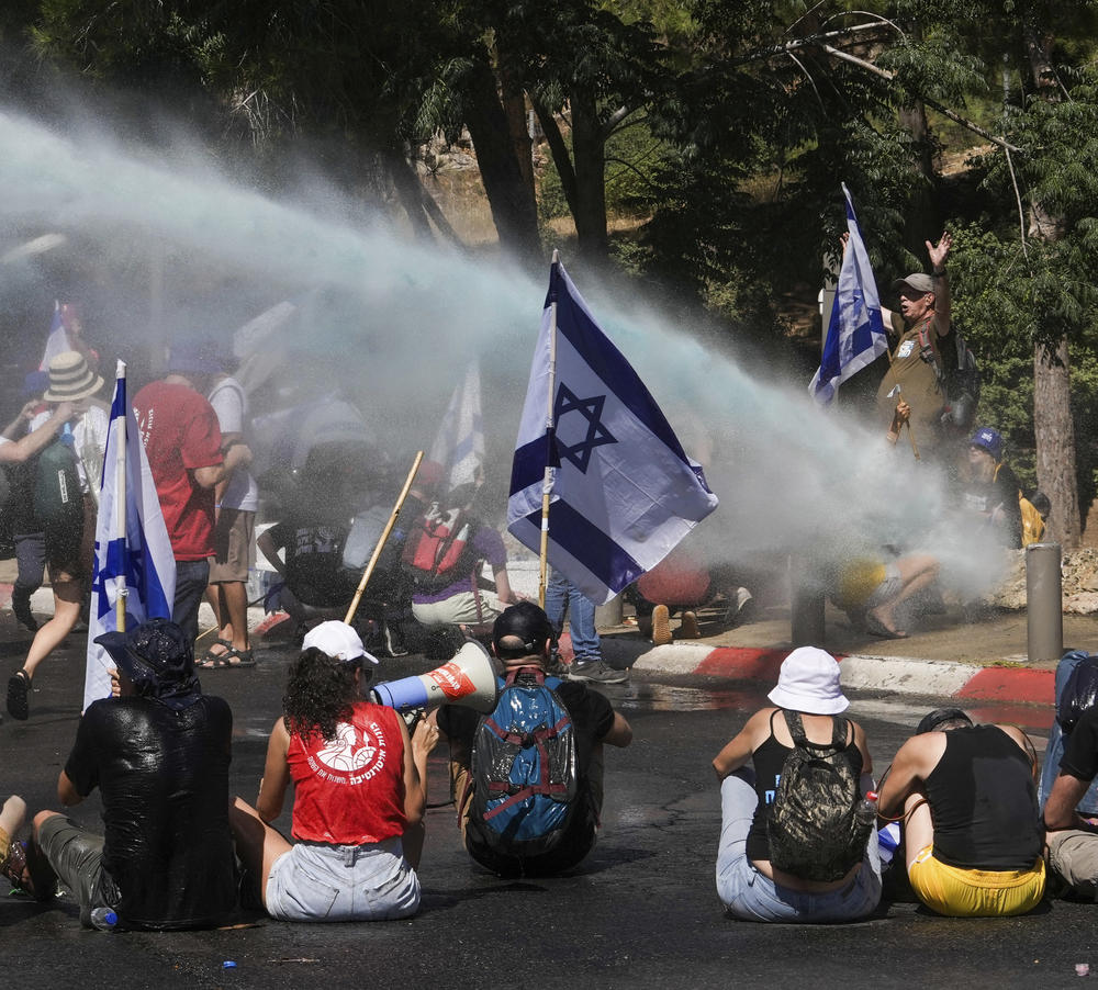 Israeli police use water cannon to disperse demonstrators blocking the road leading to the Knesset, Israel's parliament, during a protest against plans by Prime Minister Benjamin Netanyahu's government to overhaul the judicial system, in Jerusalem, Monday, July 24, 2023.