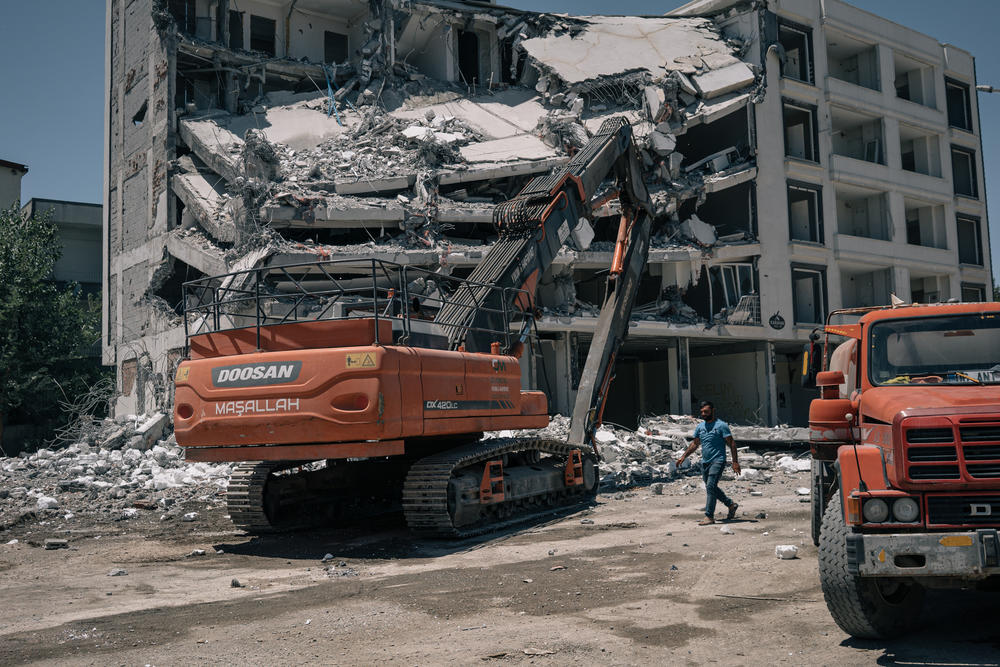 A man walks by a severely damaged building in Adiyaman.