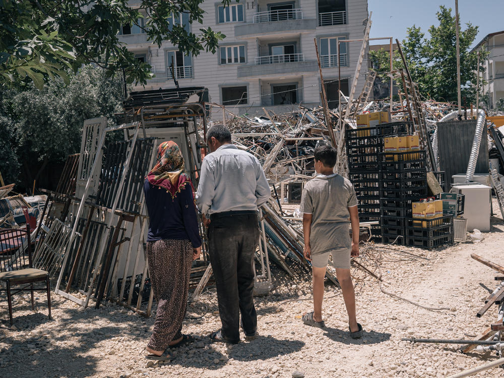 Emine, her husband and child search through materials recovered from destroyed buildings in Adiyaman.