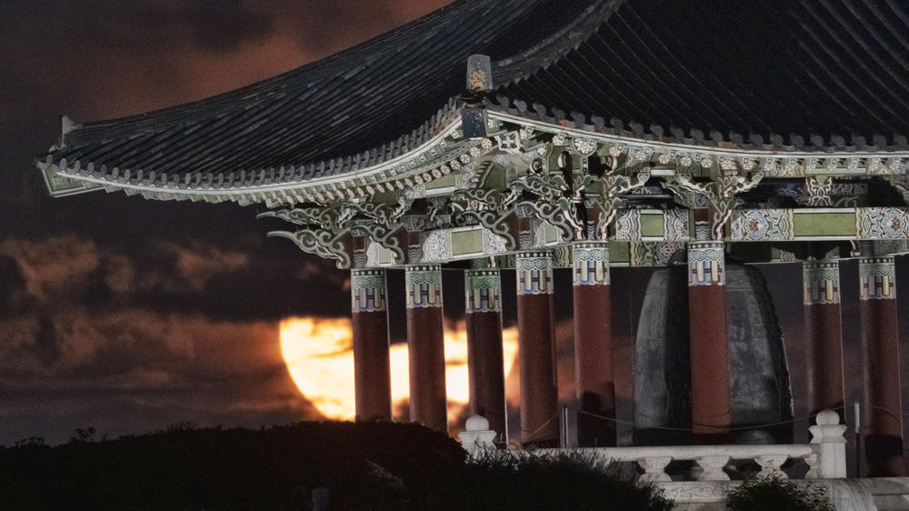 The full moon rises behind the Korean Bell of Friendship pavilion in Angel's Gate Park in Los Angeles.