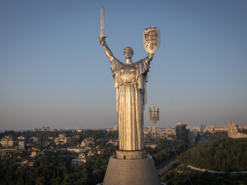 Workers install the Ukrainian coat of arms on the shield in the hand of the country's tallest stature, the Motherland Monument, after the Soviet coat of arms was removed, in Kyiv, Ukraine, Sunday, Aug. 6, 2023. Ukraine is accelerating efforts to erase the vestiges of centuries of Soviet and Russian influence from the public space.