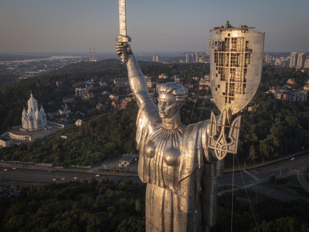 Workers install the Ukrainian coat of arms on the country's tallest statue, the Motherland Monument, after the Soviet coat of arms was removed, in Kyiv, Sunday. Ukraine is accelerating efforts to erase the vestiges of Soviet and Russian influence, pulling down monuments and renaming streets.