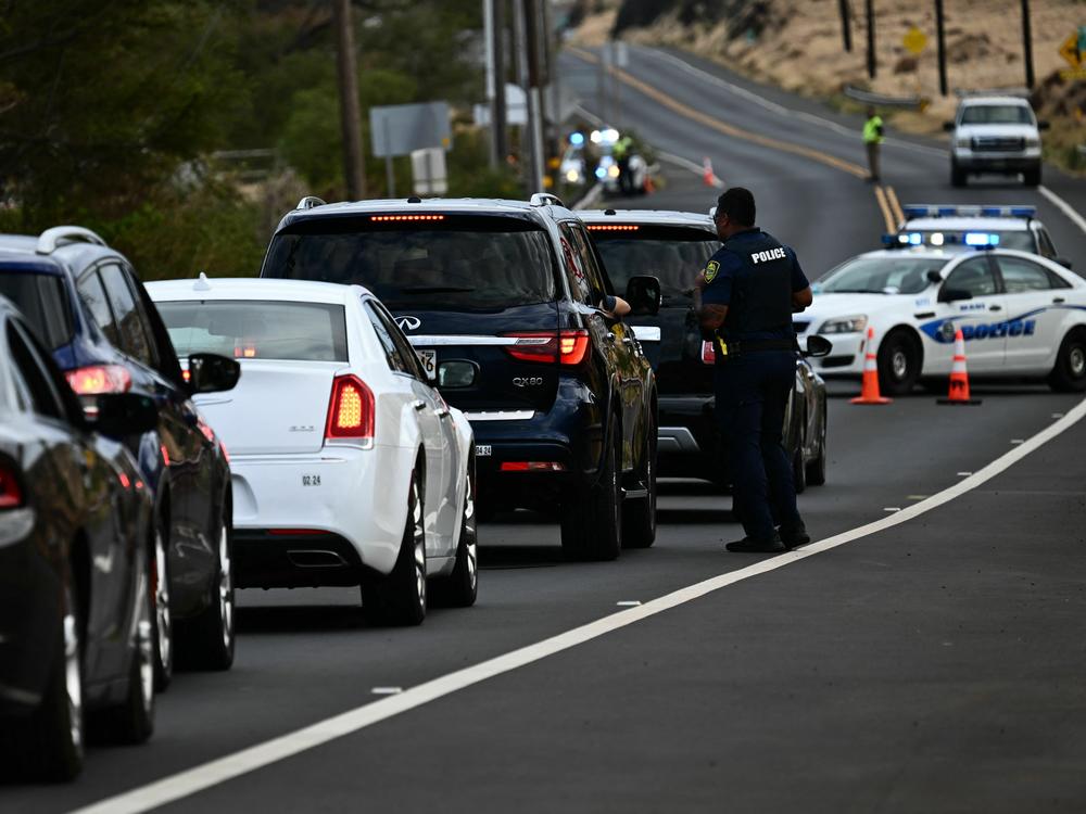 A Maui police officer blocks a road to prevent residents and visitors from driving to Lahaina in western Maui on Thursday.