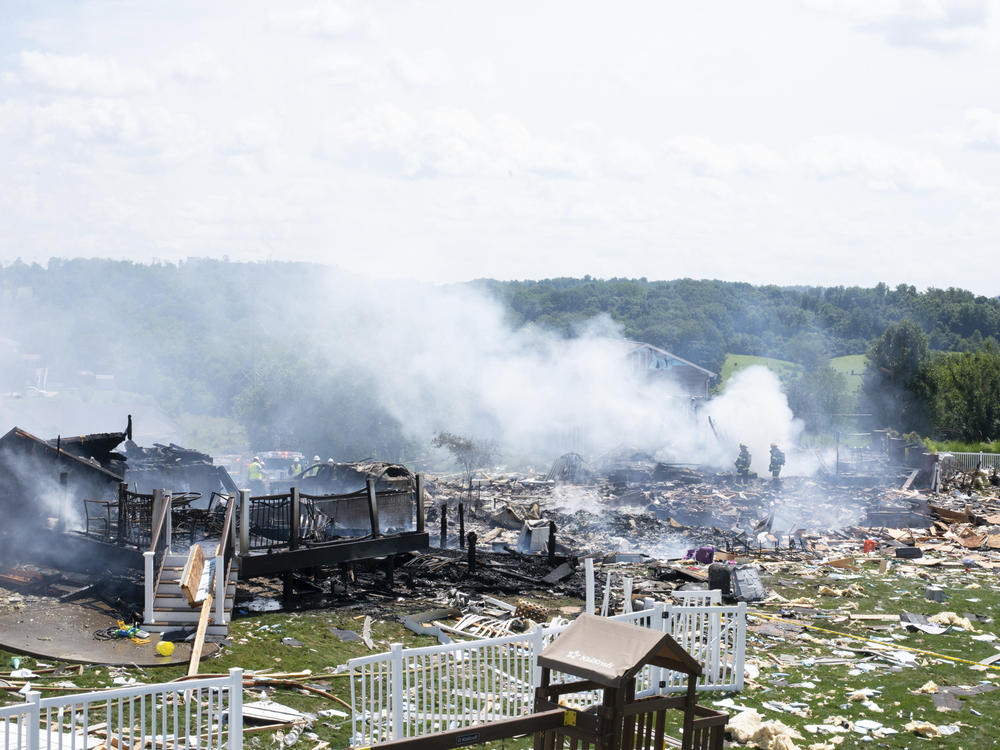 Two firefighters stand on the debris around the smoldering wreckage of the the three houses that exploded near Rustic Ridge Drive and Brookside Drive in Plum, Pa., on Saturday.
