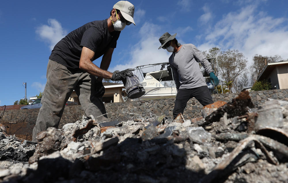 Brook Cretton (L) and Spencer Kim (R) sift through the rubble of a home that was destroyed by wildfire on August 12 in Kula, Hawaii.