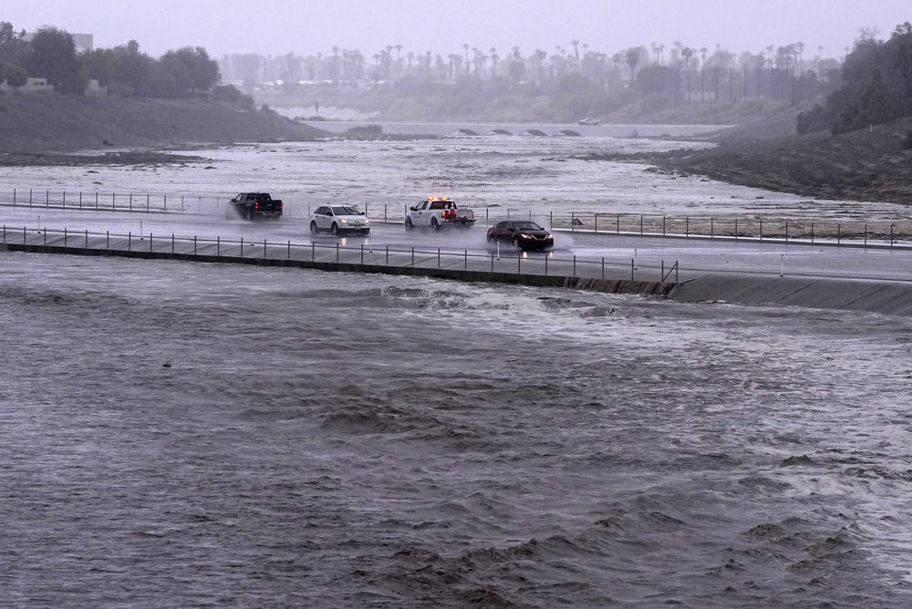 Sun., Aug. 20: Vehicles cross over a flood control basin that has almost reached the street, in Palm Desert, Calif.