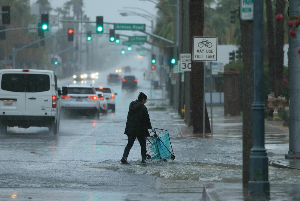 Sun., Aug. 20: A person pushes a cart on a flooded street as Tropical Storm Hilary heads north near Palm Springs, California.