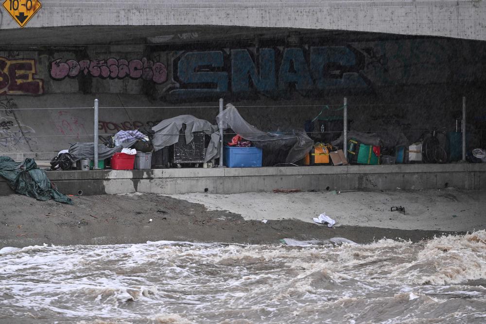 Sun., Aug. 20: Tents and belongings of unhoused people are seen near the rushing water of the Los Angeles River, near Griffith Park.