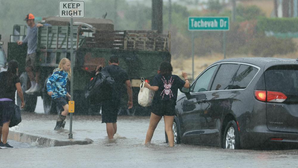 Motorists leave their vehicle stuck on a flooded road in Palm Springs, Calif., during Tropical Storm Hilary on Sunday.