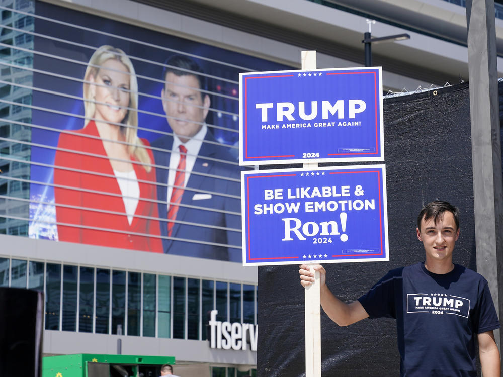 A former president Donald Trump supporter stands near the Fiserv Forum as set up continues for the upcoming Republican presidential debate Tuesday, Aug. 22, 2023, in Milwaukee. (AP Photo/Morry Gash)