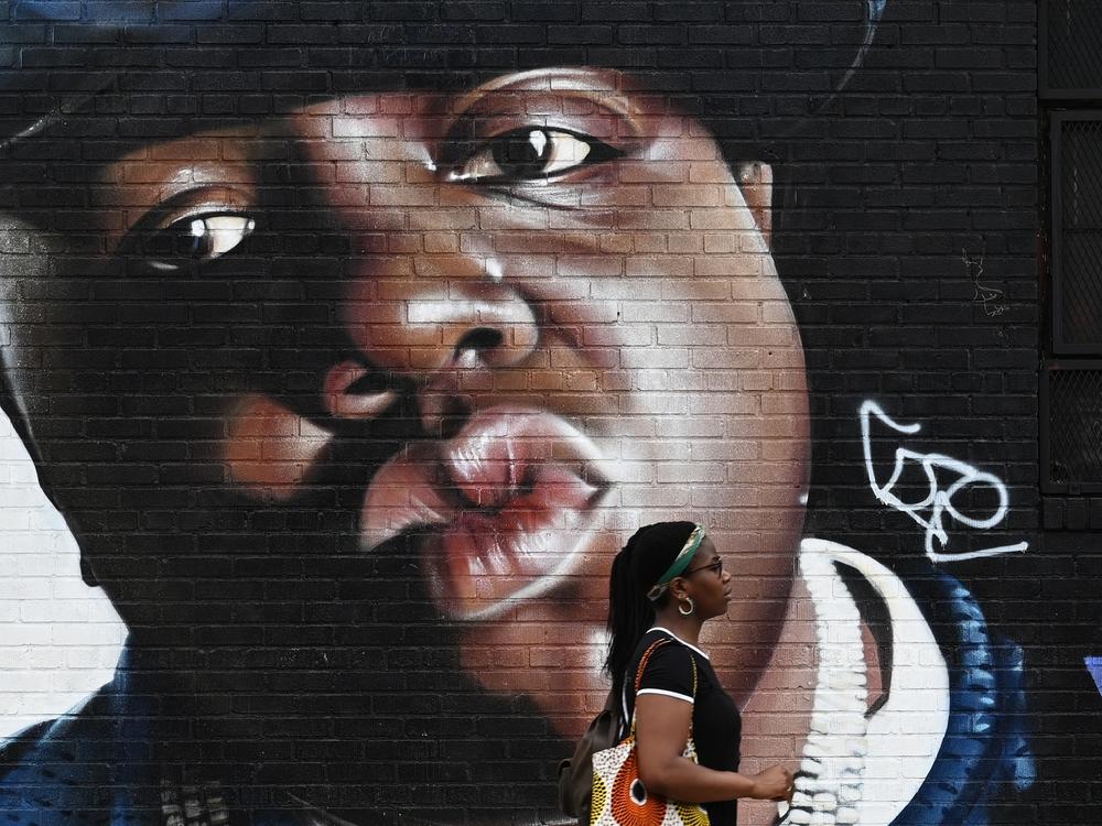 A woman passes by a mural of the rapper Biggie Smalls on a wall in the Bushwick section of Brooklyn.