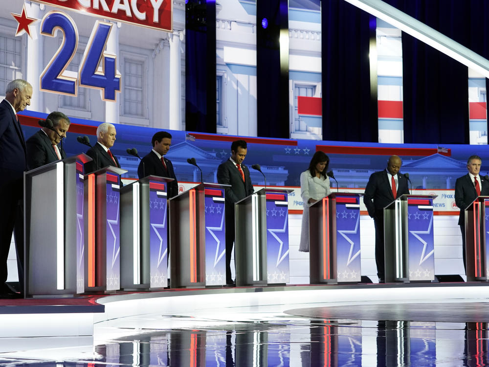 Republican presidential candidates stand on stage and listen to a prayer before a Republican presidential primary debate hosted by FOX News Channel Wednesday, Aug. 23, 2023, in Milwaukee.