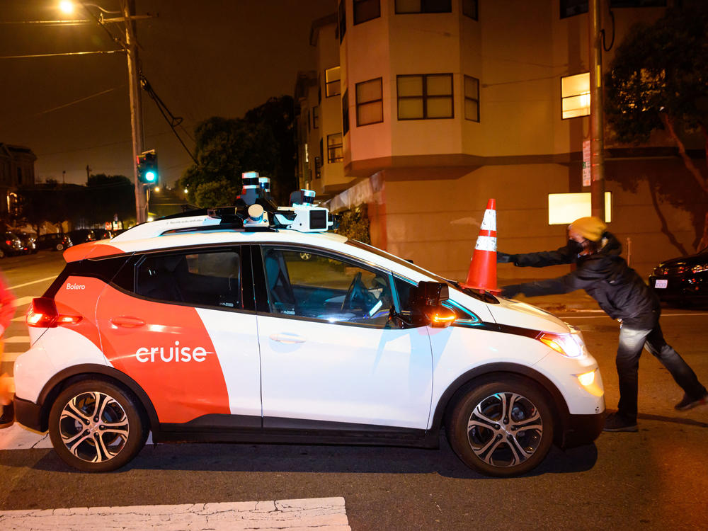 Members of Safe Street Rebel place a cone on a self-driving Cruise car in San Francisco.