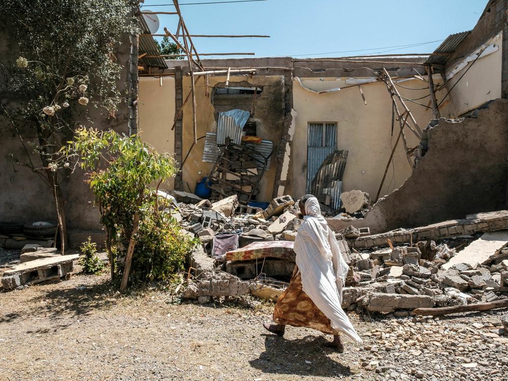 A woman walks in front of a house damaged by shelling in the city of Wukro, in Tigray, Ethiopia. A new report indicates that military forces have engaged in hundreds of sexual assaults on girls and women.