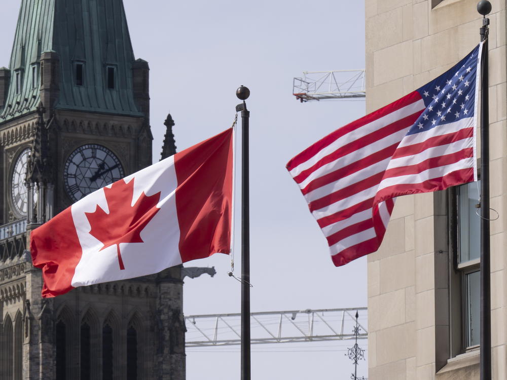 The Canadian and U.S. flags are displayed on lamp posts in the downtown area, March 22, 2023, near Parliament Hill in Ottawa, Ontario.