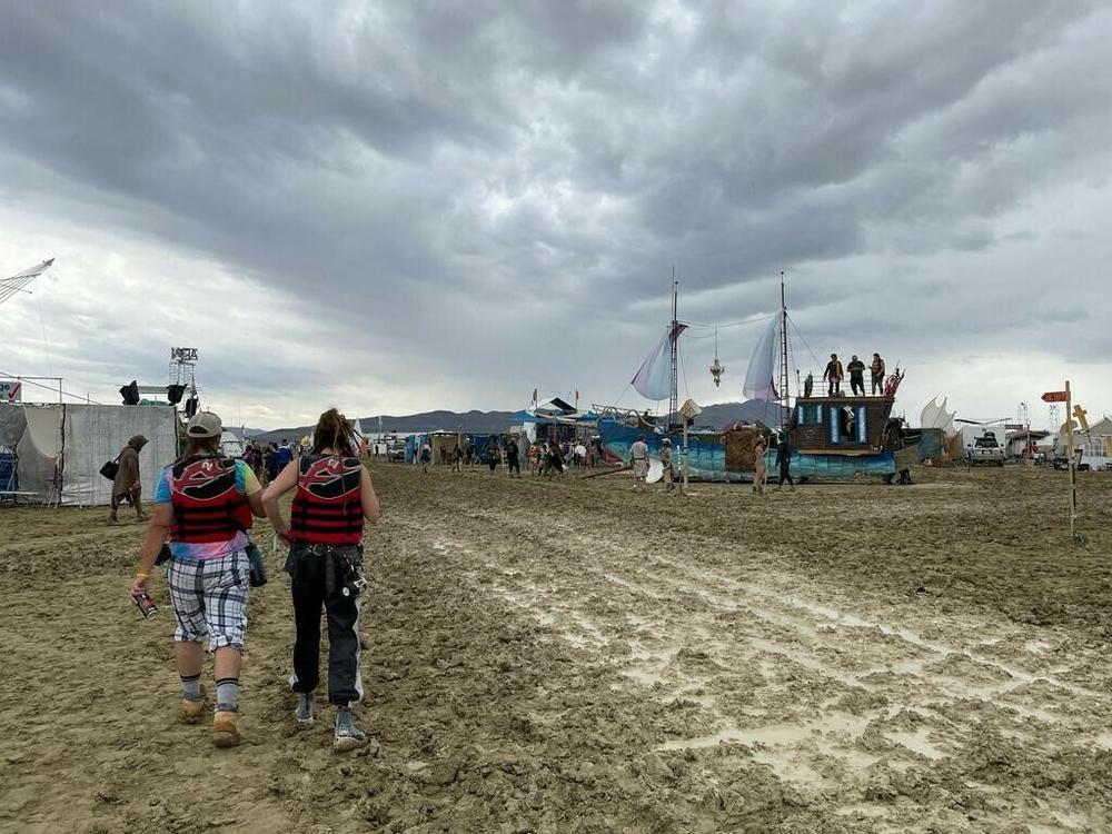 Burning Man attendees walk through a muddy desert plain on Saturday, after heavy rains pelted the annual Nevada festival.