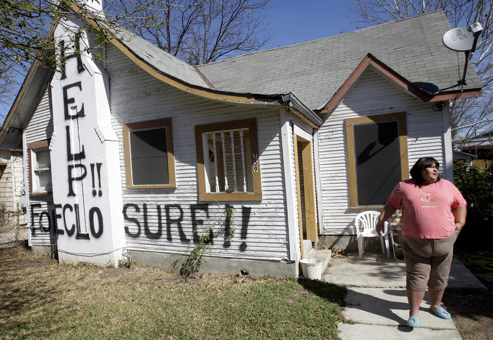 Mary Ann Herrera stands outside her home in San Antonio, on Feb. 23, 2009. Under the threat of foreclosure, Herrara's brother painted the words 
