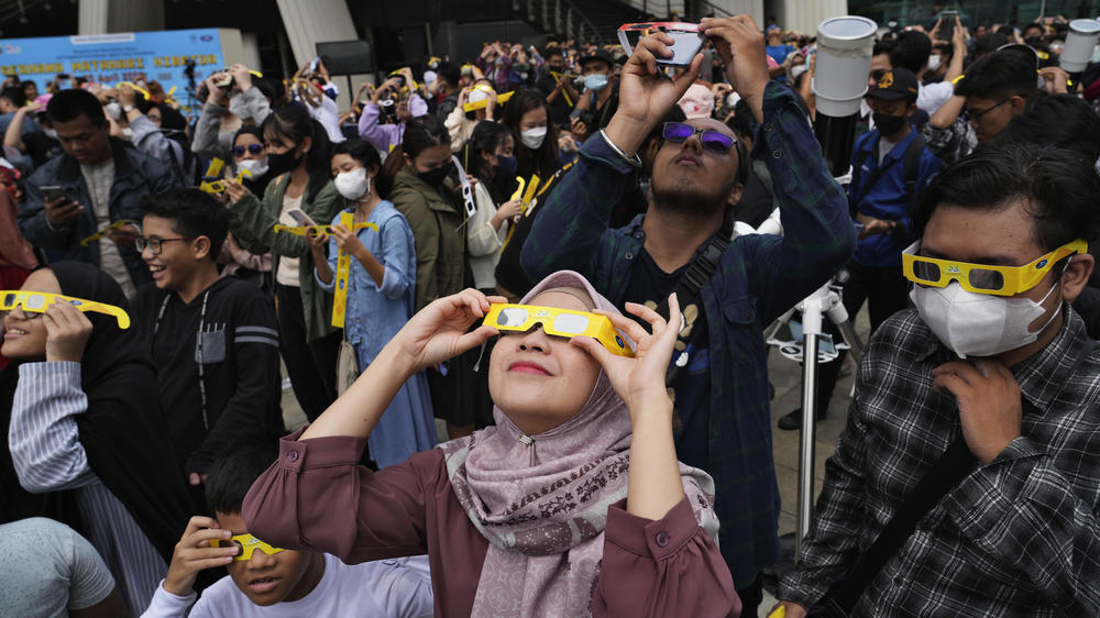 People use protective glasses to watch solar eclipse in Jakarta, Indonesia, Thursday, April 20.