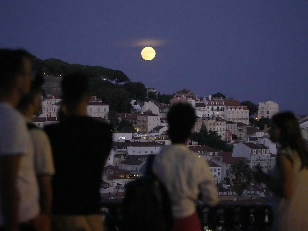 People watch a supermoon rise above Lisbon, Portugal, on Aug. 30.