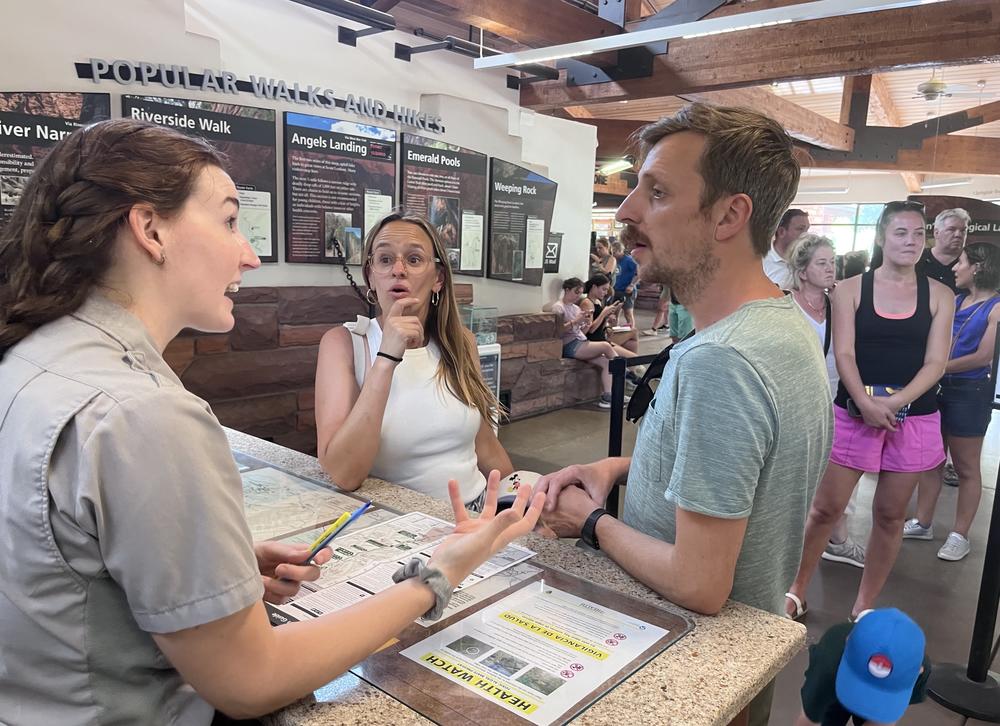 Park ranger Jenn Cook answers questions from Bram and Elke Vanderelst at the Zion Canyon Visitor Center. Over 23,000 people work in Utah's national parks, according to the National Park Service.