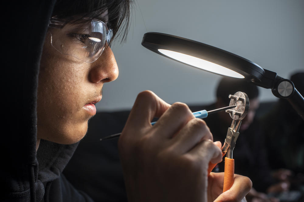 Kevin Mendoza, 15, a member of Team 8048 Churrobots of East Palo Alto, Calif., cleans dust particles off a gearbox component.