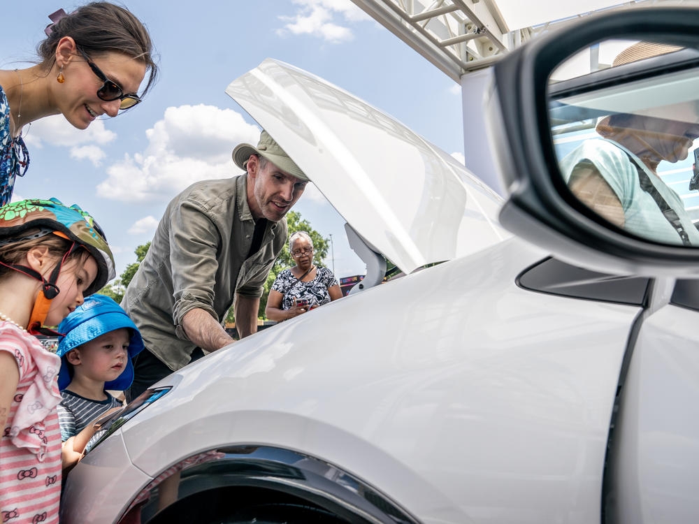 A family inspects the engine of a new Toyota Prius model during the Electrify Expo In D.C. in Washington, D.C., on July 23, 2023. Getting an electric vehicle tax credit of up to $7,500 will get a lot easier next year.