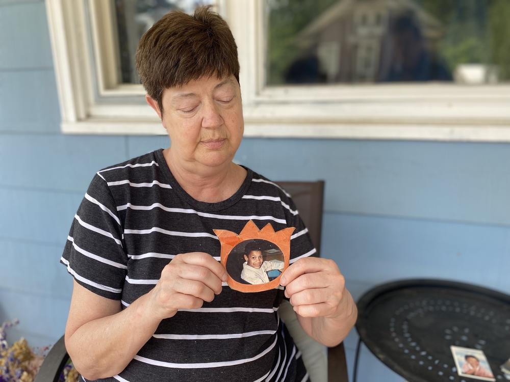 Susan Hurlburt, pictured here in 2022, holds a childhood photo of her son, Neil Harris Jr.