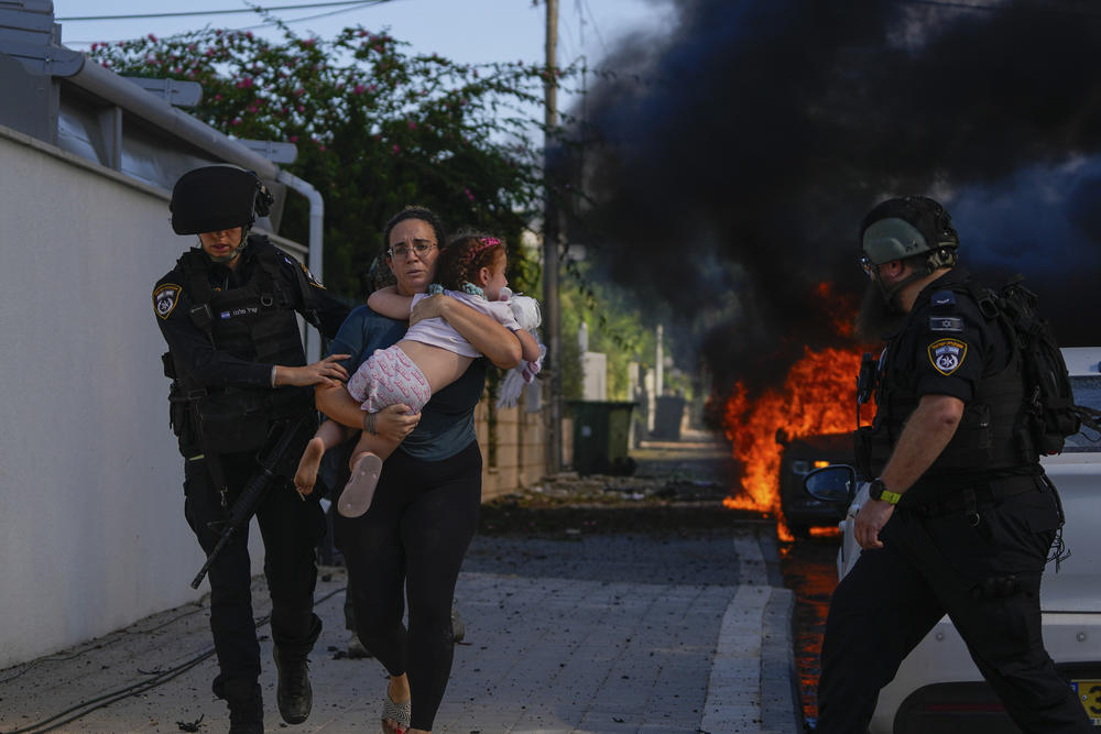 Sat, Oct. 7: Police officers evacuate a woman and a child from a site hit by a rocket fired from the Gaza Strip, in Ashkelon, southern Israel.