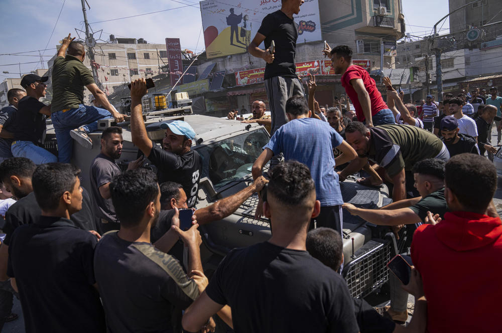 Sat., Oct. 7: Palestinians gather around an Israeli army vehicle that Palestinian militants drove from Israel into Gaza, in Shejaiya, Gaza Strip.