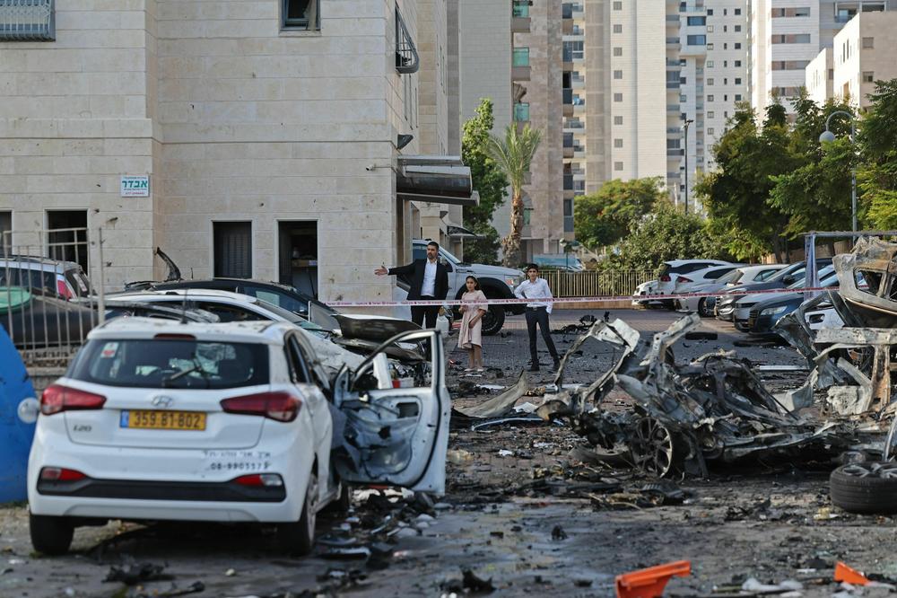 Residents walk past burnt-out vehicles in Ashkelon following a rocket attack from the Gaza Strip into Israel on Oct. 7, 2023.