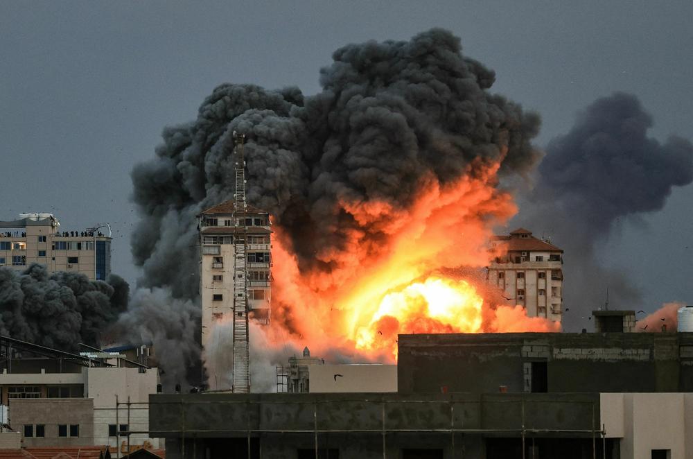 Sat., Oct. 7: People standing on a rooftop watch as a ball of fire and smoke rises above a building in Gaza City.