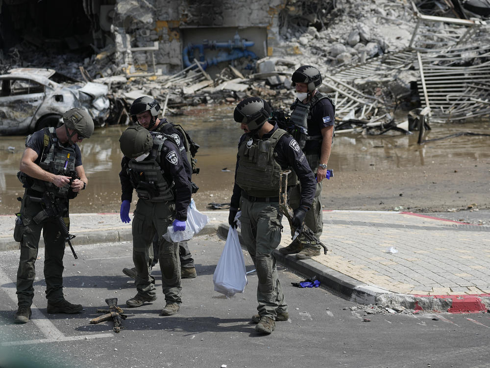 Israeli police retrieve weapons used by militants outside a police station that was overrun by Hamas gunmen on Saturday, in Sderot, Israel, on Sunday. Hamas militants stormed over the border fence Saturday, killing hundreds of Israelis in surrounding communities.