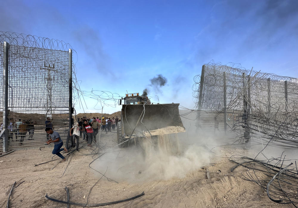 Sat., Oct. 7: Palestinians break over a fence with the help of a digger.