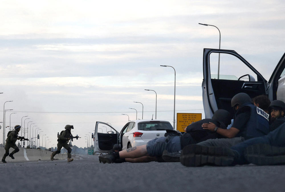 Sat., Oct. 7: Journalists take cover behind cars as Israeli soldiers take position during clashes with Palestinian fighters near the Gevim Kibbutz, close to the border with Gaza.
