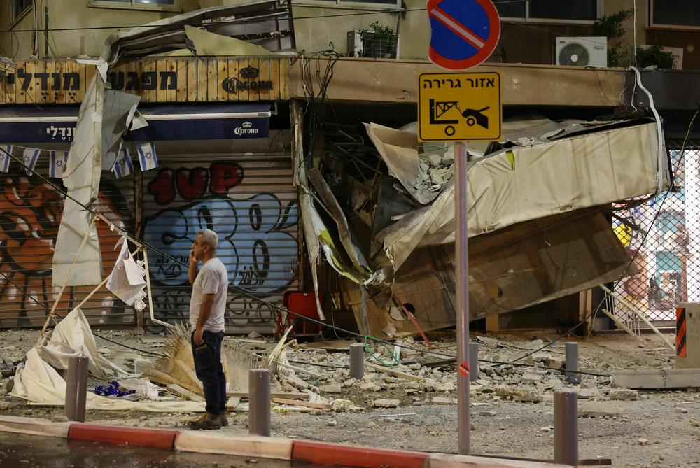 Sat., Oct. 7: A man stands in front of a damaged shop in Tel Aviv.
