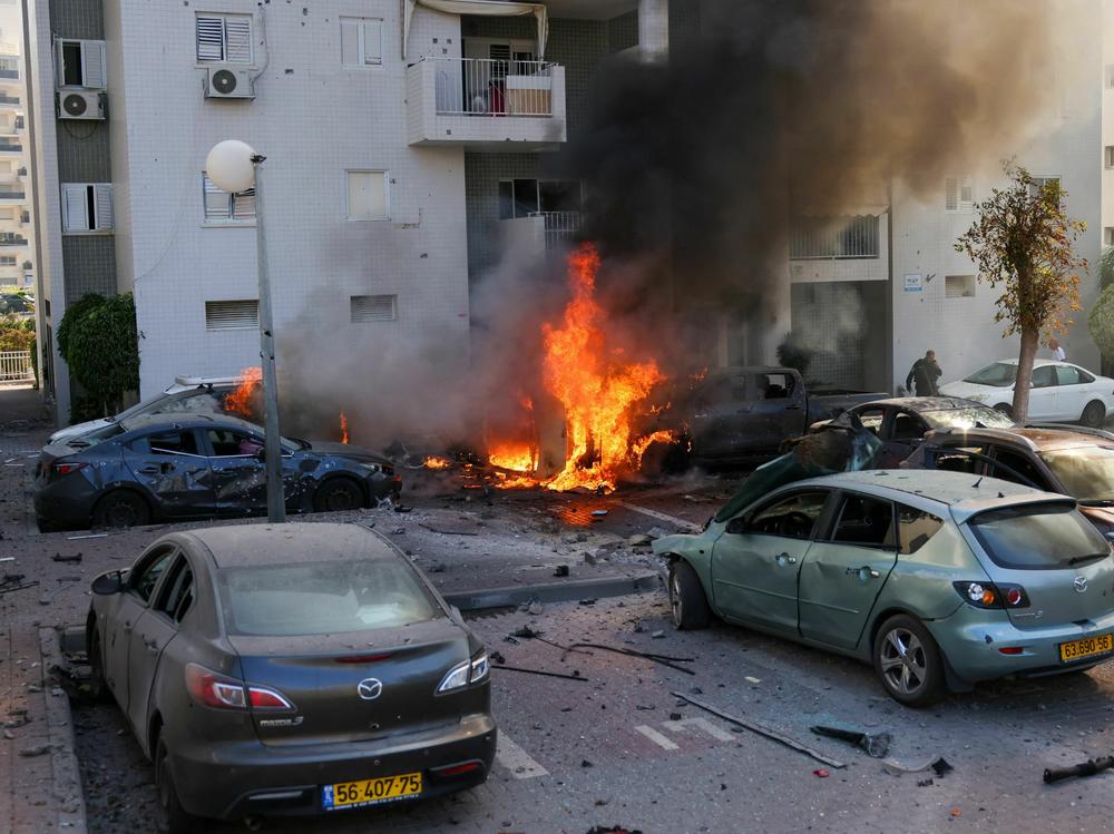 A member of the Israeli security forces stands near burning cars following a rocket attack from the Gaza Strip in Ashkelon, southern Israel, on Oct. 7.
