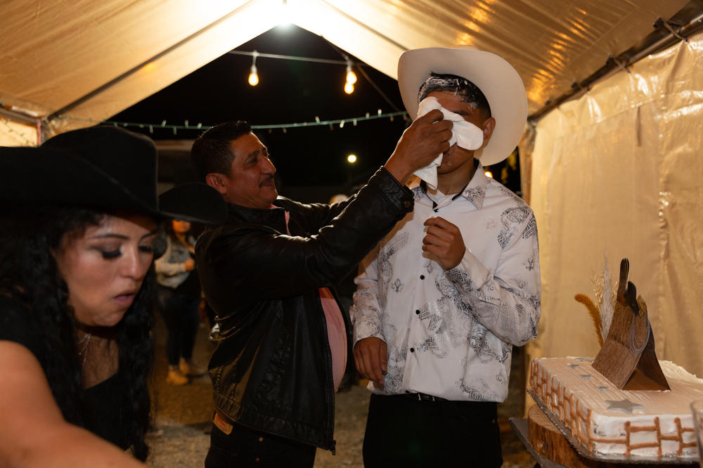 A family member cleans Kevin's face after the <em>mordida</em>, a Mexican tradition when the birthday boy or girl's face is shoved into a cake for them to take the first bite as they're surrounded by their loved ones chanting <em>Mor-di-da! Mor-di-da!</em>