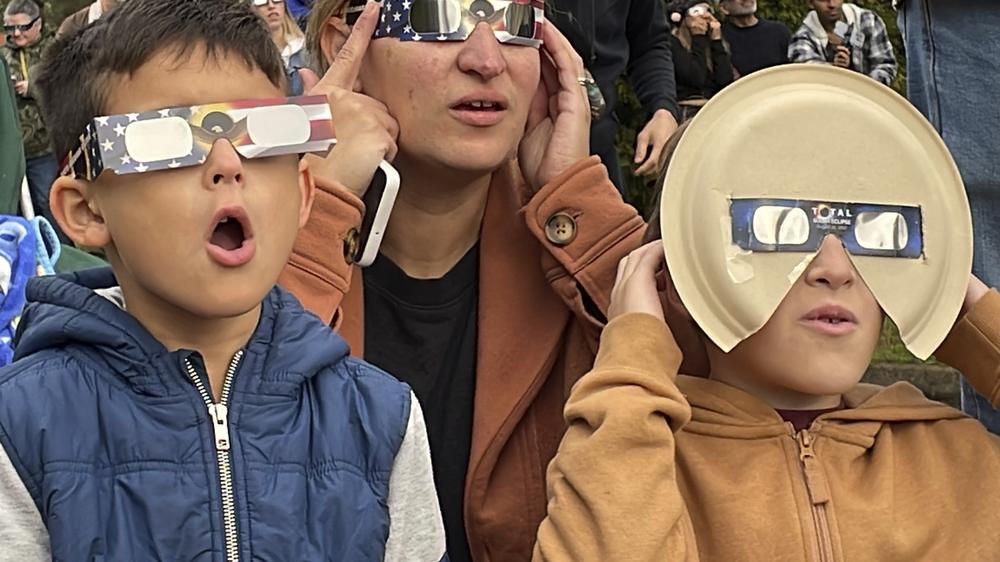 Samia Harboe, her son Logan and her friend's son wear eclipse glasses during totality of the annular solar eclipse in Eugene, Ore., on Saturday.