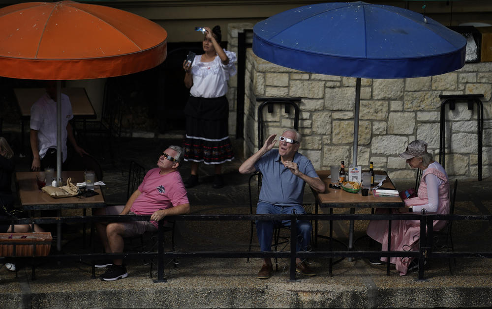 Diners and restaurant workers along the Riverwalk in San Antonio, Texas, use special glasses to keep watch as the moon moves in front of the sun on Saturday.