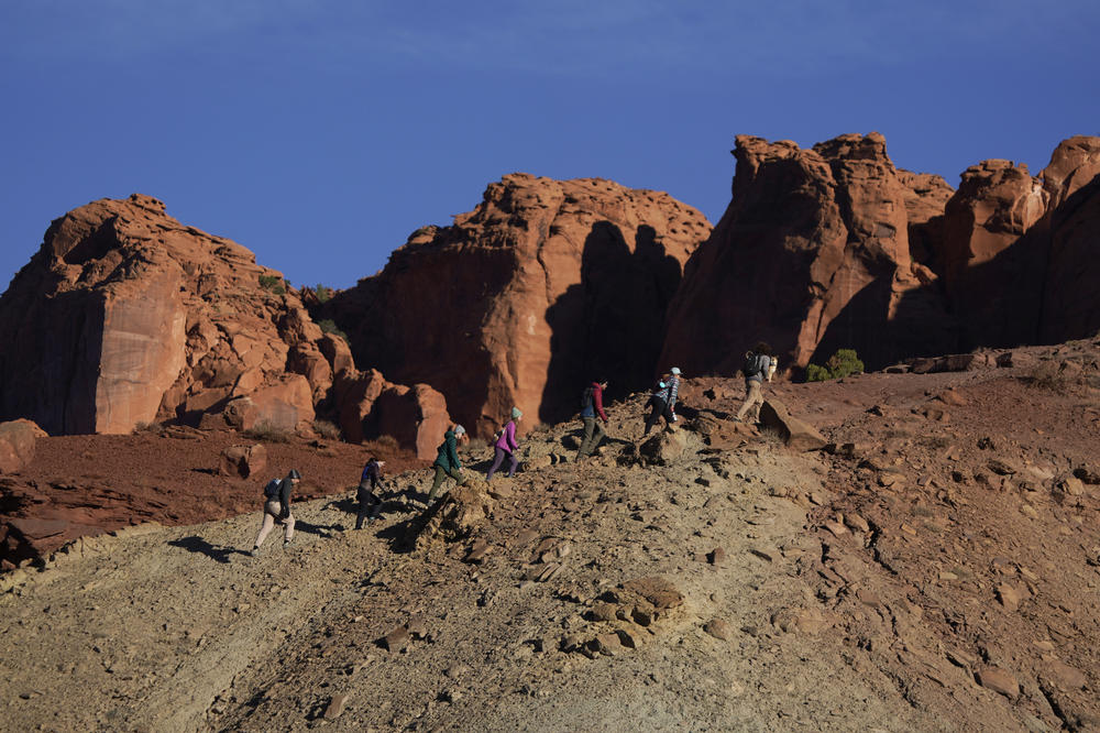 A group of people walk up a ridge at sunrise to find a spot to view the annular solar eclipse that began shortly after 9 a.m. on Saturday in Capitol Reef National Park, Utah.