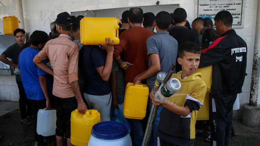 Palestinian citizens fill jugs and cans at a water station in Khan Younis, south of Gaza City, on Saturday. Gaza Strip residents are struggling with water and electricity outages due to the war between Israel and Hamas.