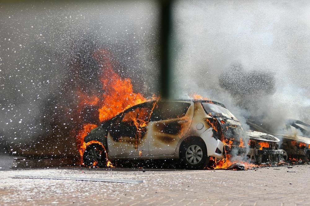 Cars are seen on fire following a rocket attack from Gaza in Ashkelon, southern Israel, on October 7.