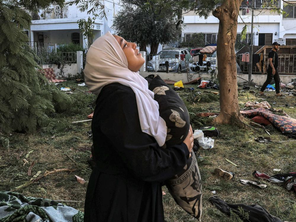 A woman reacts while holding a pillow as she stands amid debris outside the site of Al Ahli hospital in central Gaza on Wednesday. The blast killed hundreds.