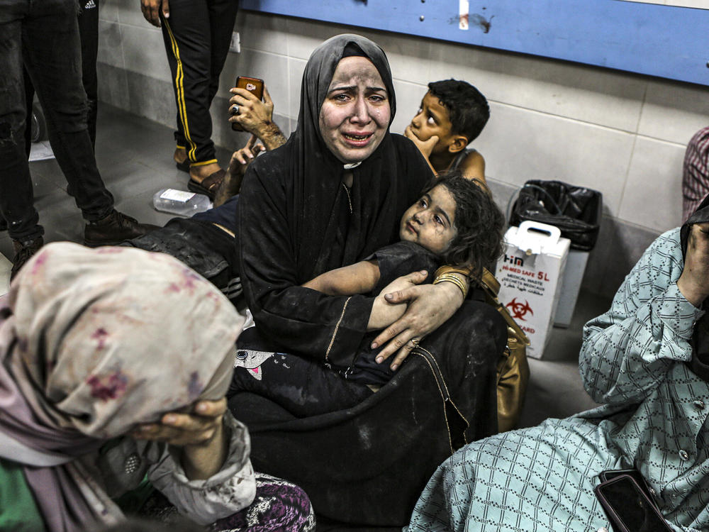 Wounded Palestinians sit in al-Shifa hospital in Gaza City, central Gaza Strip, after arriving from Al-Ahli hospital following an explosion there, on Tuesday.
