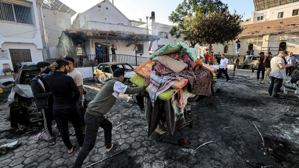 A man pushes a cart carrying salvaged mattresses, pillows and sheets at the site of Al Ahli Arab hospital in central Gaza on Wednesday.